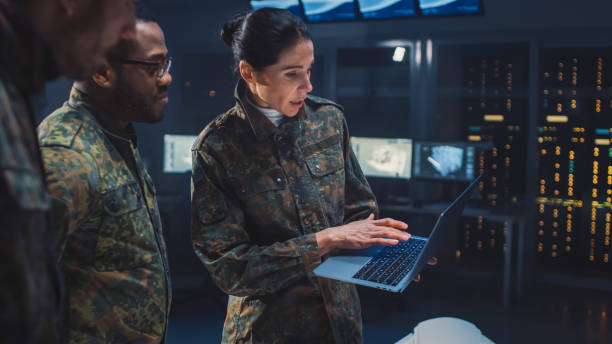 International Team of Military Personnel Have Meeting in Top Secret Facility, Female Leader Holds Laptop Computer Talks with Male Specialist.